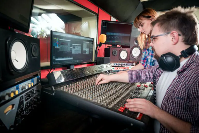 Music engineer and musician working together in recording studio using mixing desk